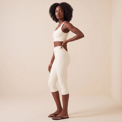 Legging blanc 3/4 de profil, main dans le dos : taille haute ajustée et ligne galbée de la hanche au genou