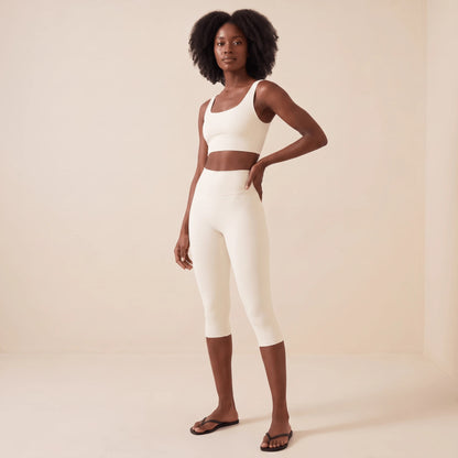 Legging capri blanc femme de trois quarts face, main sur la hanche : taille haute marquée et coupe ajustée tight fit