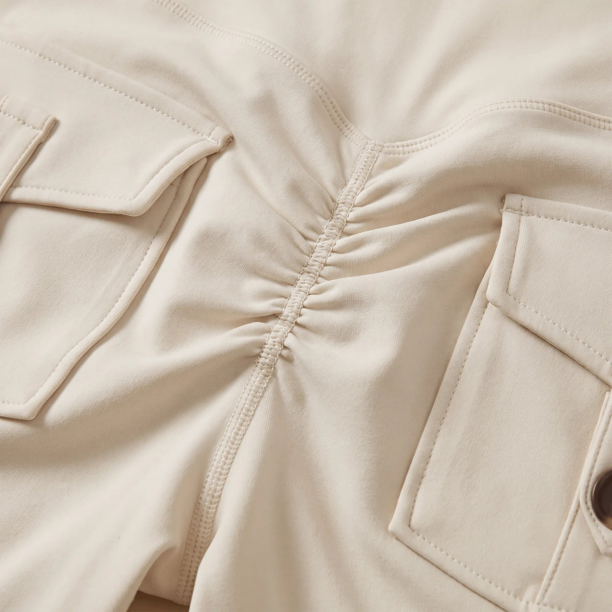 Détail du tissu doux du legging blanc scrunch : couture centrale froncée au bas du dos entre deux poches à rabat