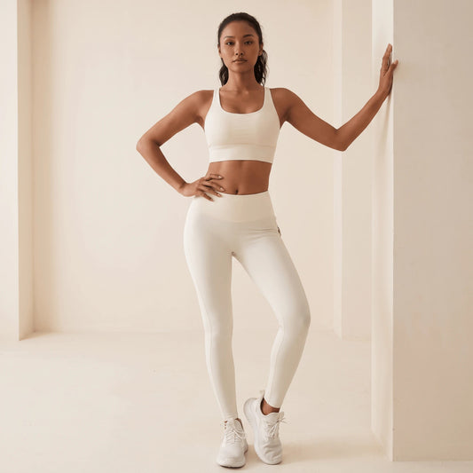Legging blanc avec poches arrière en blanc cassé, vue de face en pied : taille haute, coupe ajustée pleine longueur et brassière blanche à bretelles croisées au dos