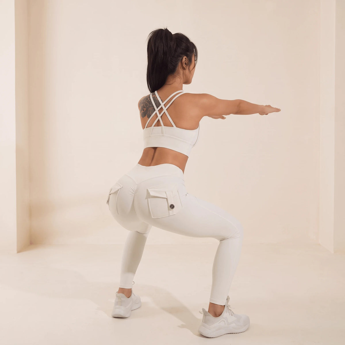 Legging blanc effet galbant en squat de dos : tissu élastique qui suit le mouvement, poches à rabat et couture scrunch