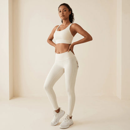 Legging blanc taille haute de trois quarts face, mains sur les hanches : ceinture haute et poche à rabat visible sur le côté