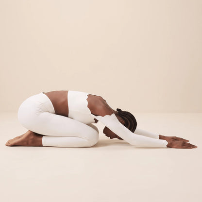 Legging yoga blanc en posture de l'enfant : maille douce et extensible, ceinture en V confortable au sol