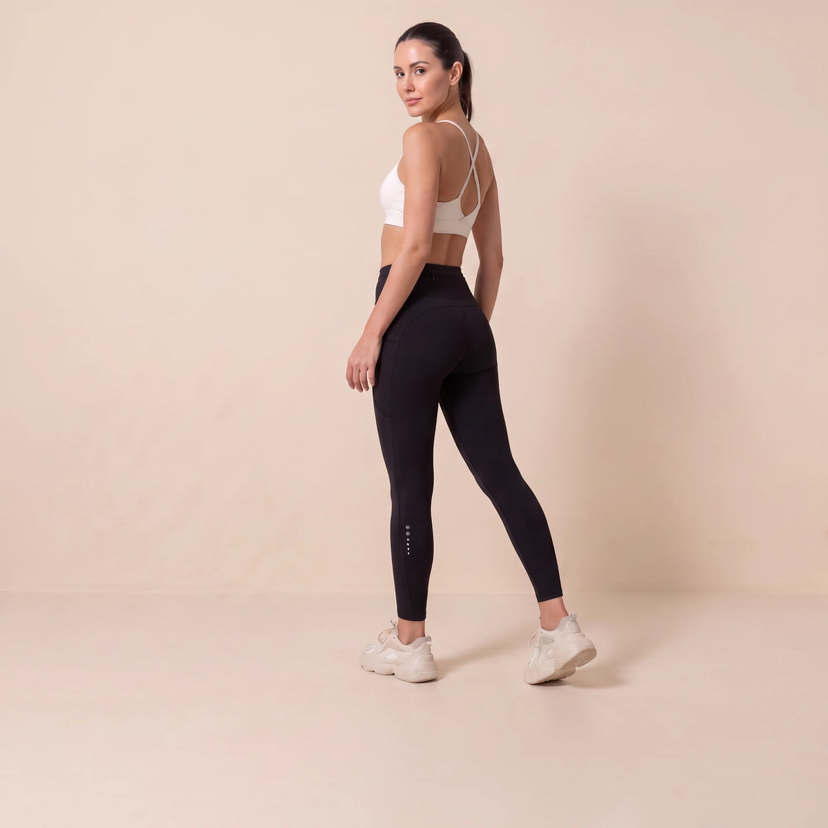 Legging compression sport femme noir vu de dos, taille haute, poche arrière et marquage réfléchissant sur le mollet