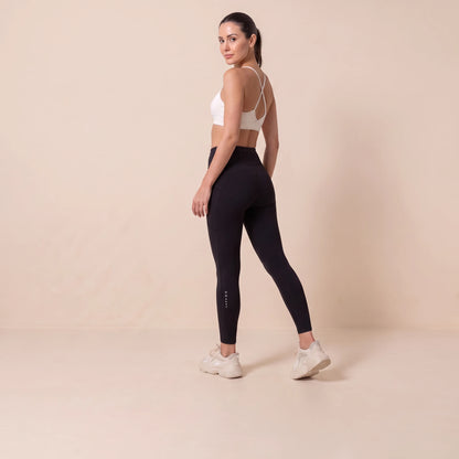 Legging compression sport femme noir vu de dos, taille haute, poche arrière et marquage réfléchissant sur le mollet
