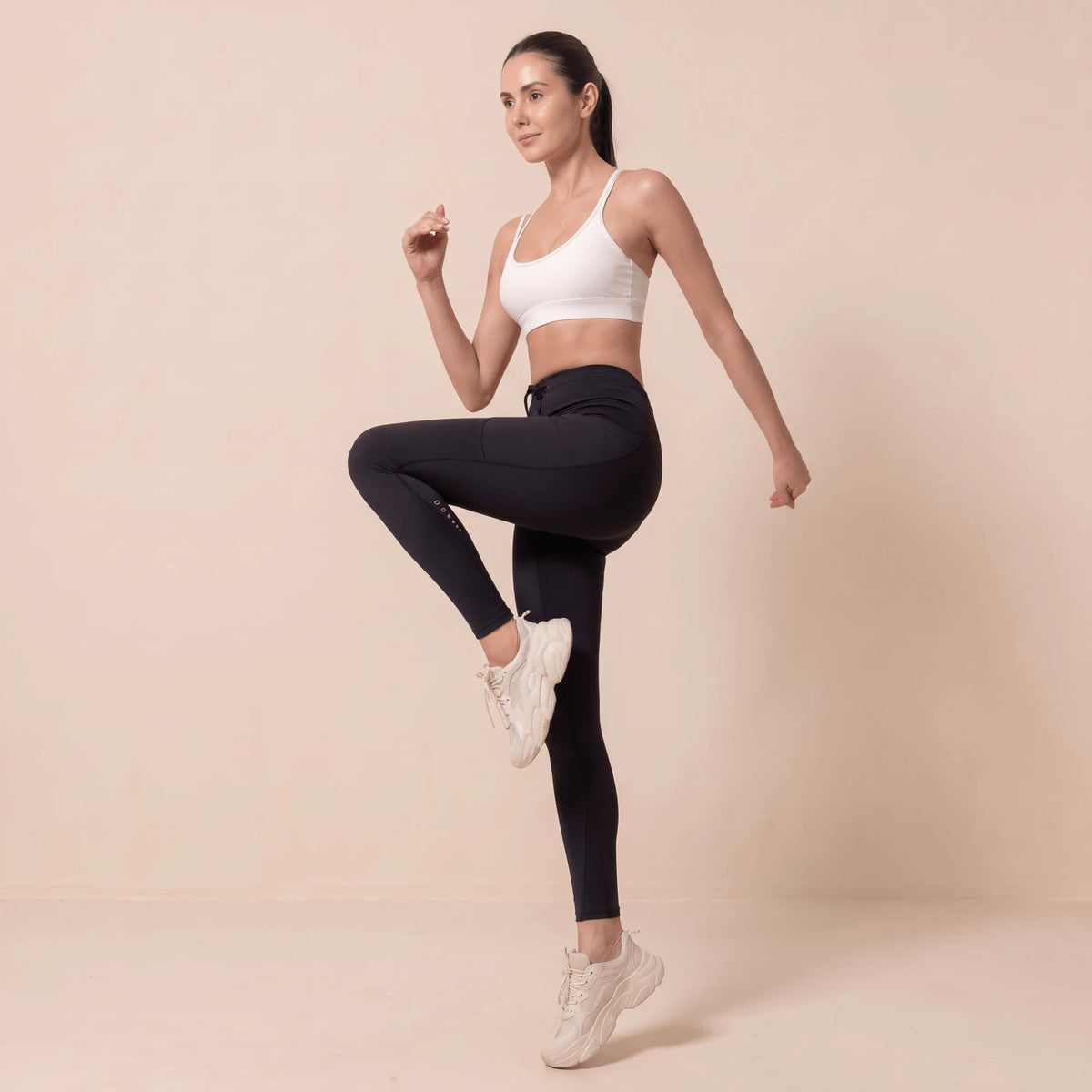 Legging compression running femme noir, genou levé, marquage réfléchissant sur la jambe