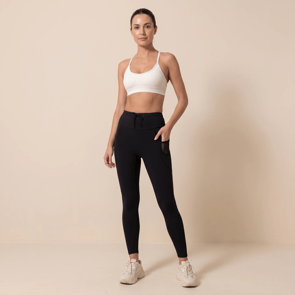Legging de compression sport femme noir, main dans la poche latérale en maille, vue de face