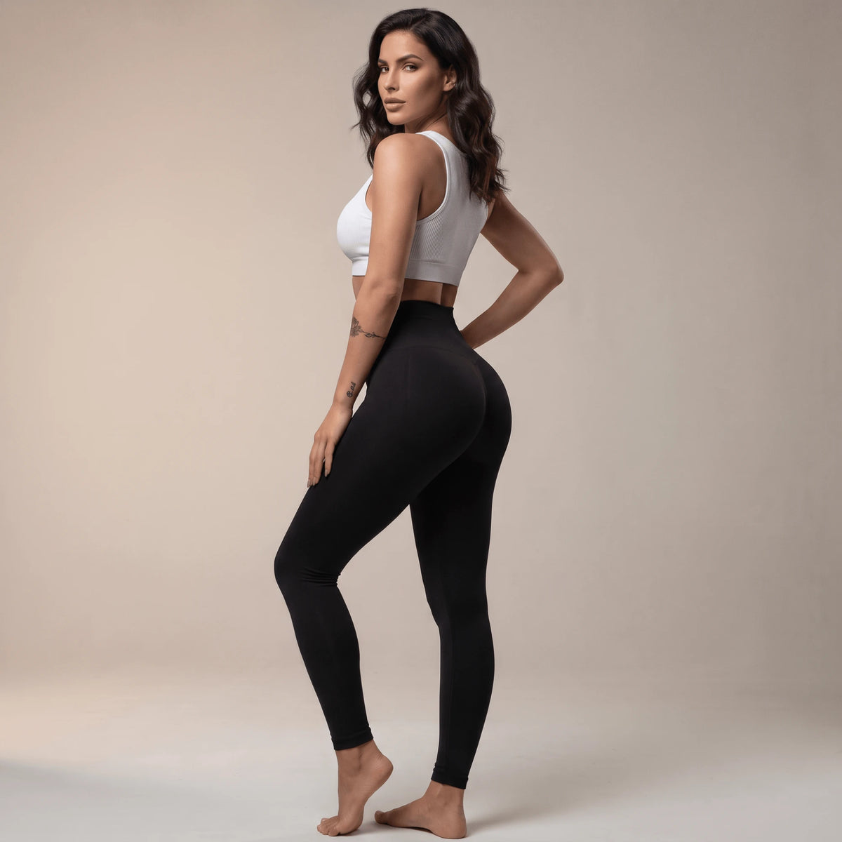 Legging de compression femme noir taille haute vu de dos, silhouette debout, studio beige