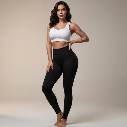 Legging de compression femme noir taille haute porté de face, main sur la hanche, ceinture large au-dessus du nombril