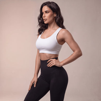 Gros plan de la ceinture haute côtelée d'un legging de compression femme noir, main sur la hanche, vue de profil