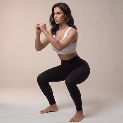 Legging de compression femme noir en squat, ceinture haute qui reste en place pendant le mouvement