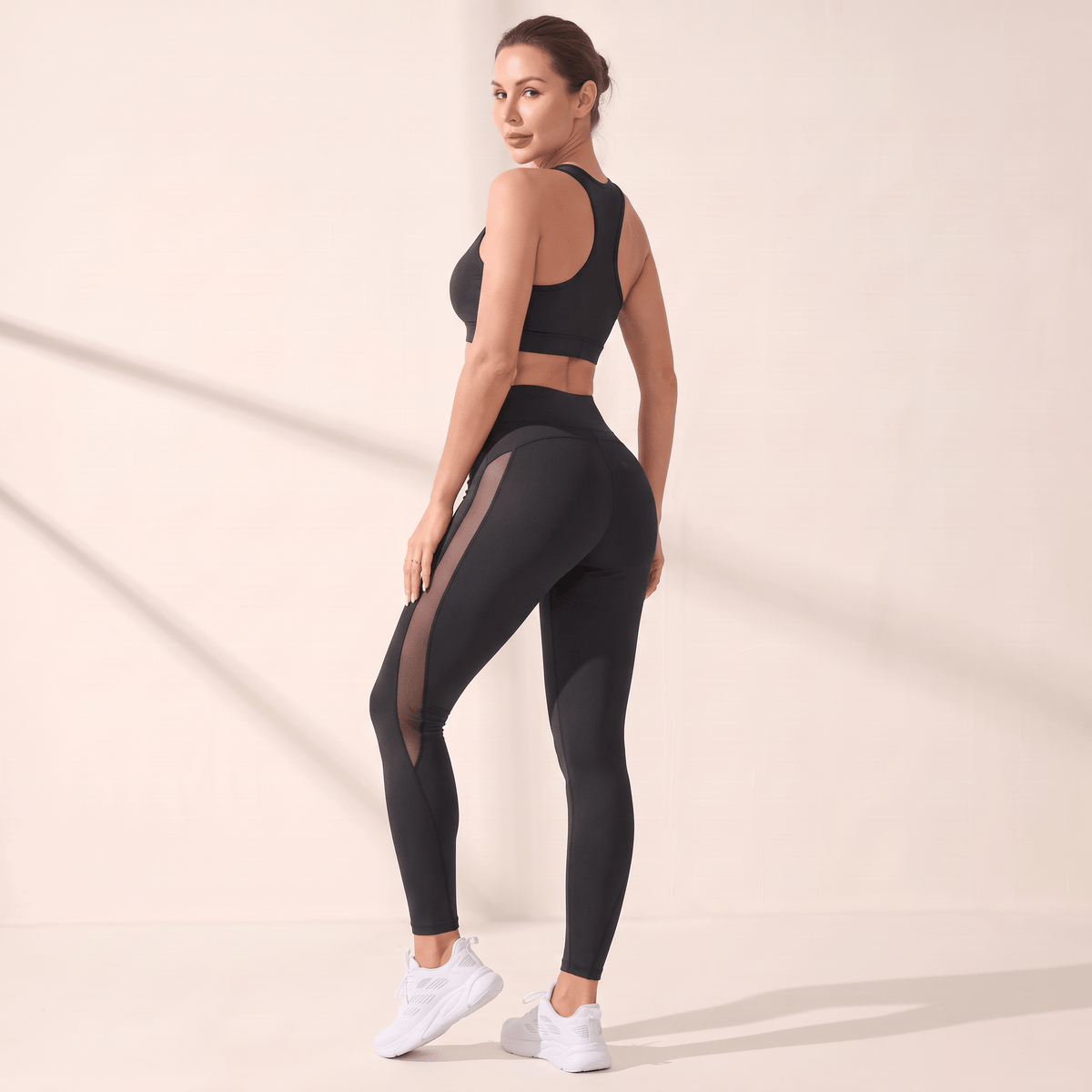 Legging noir push up femme vu de dos, couture en V et panneau mesh latéral