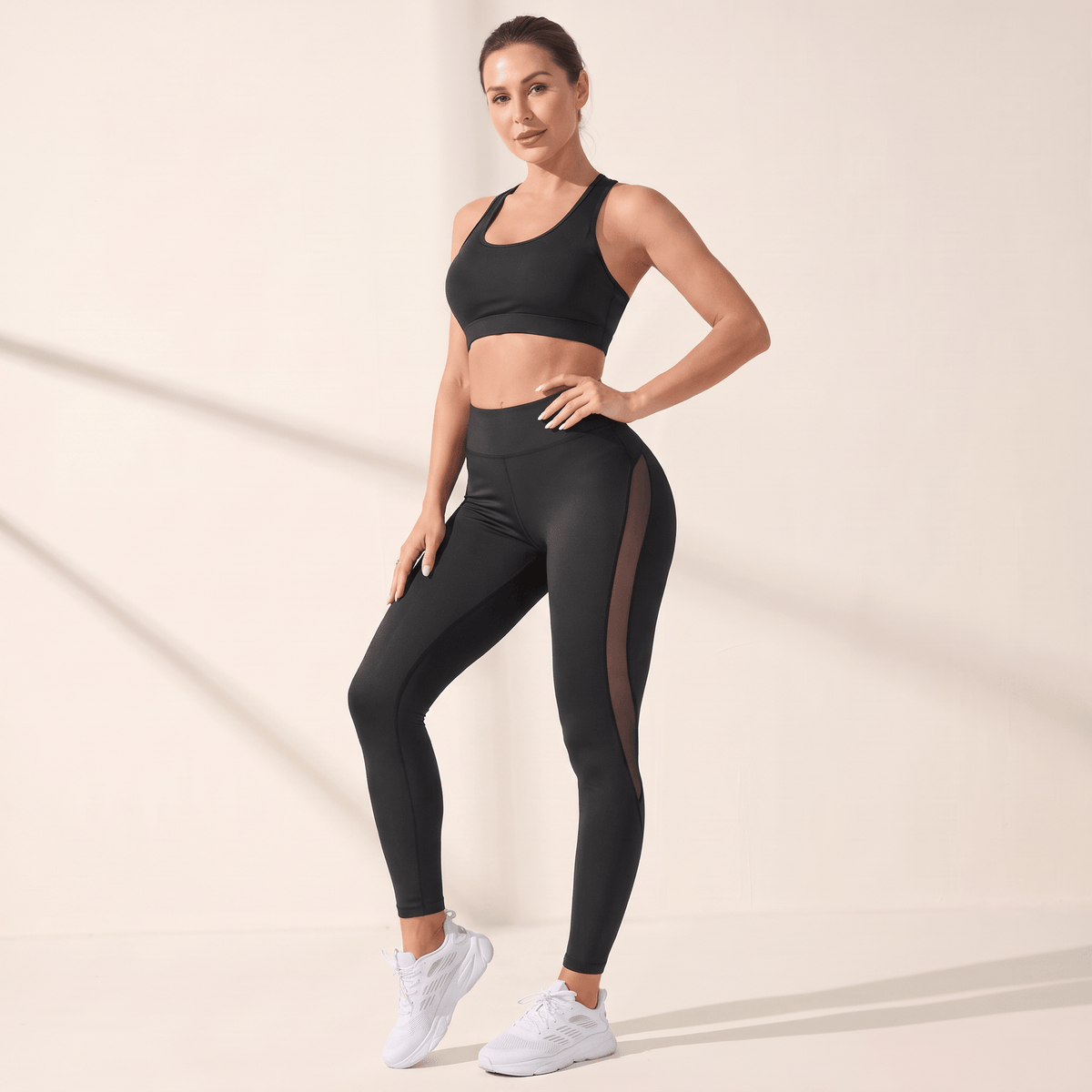 Legging femme noir taille haute avec panneaux en mesh, vu de face, main sur la hanche