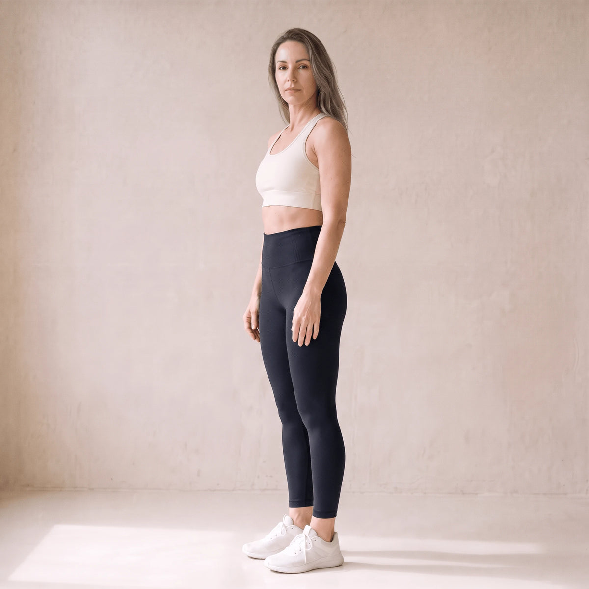 Legging fitness femme noir taille haute vu de trois quarts, ceinture haute et longueur cheville, studio crème