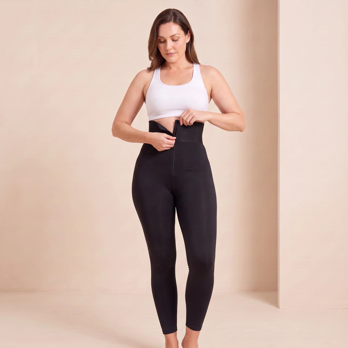 Legging fermeture éclair noir : geste de fermeture du zip de la ceinture large pour ajuster le maintien de la taille