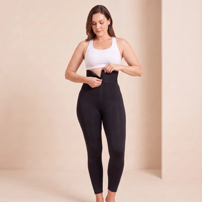 Legging fermeture éclair noir : geste de fermeture du zip de la ceinture large pour ajuster le maintien de la taille