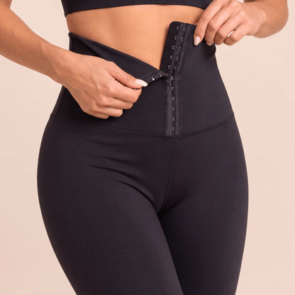 Gros plan sur la fermeture à crochets réglable d'un legging ceinture corset noir : on accroche les crochets au rang qui convient