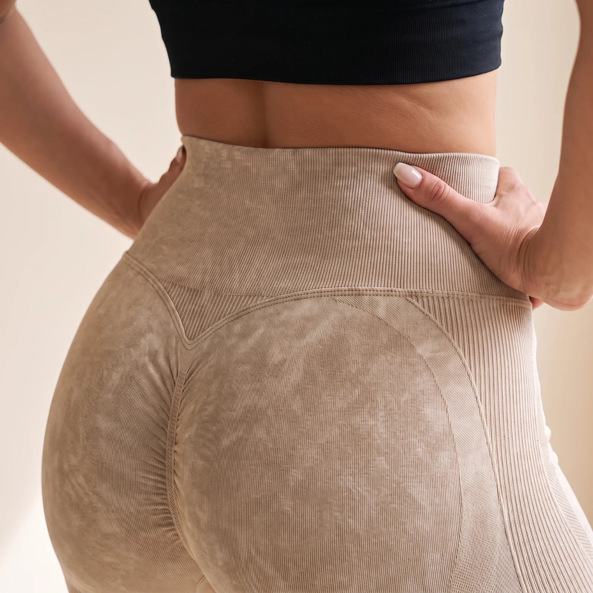 Gros plan de dos sur la ceinture côtelée et la couture en V d'un legging galbant sans couture beige