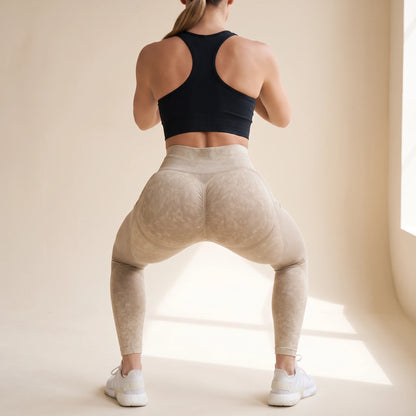 Legging galbant sans couture beige en squat vu de dos, ceinture haute et couture arrière, studio crème