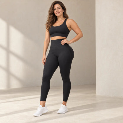 Legging sculptant noir taille haute porté de face, main sur la hanche, ceinture large compressive, brassière noire