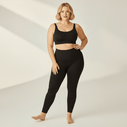 Legging Sculptant Grande Taille noir, pose etirement fitness, studio ivoire gris clair, femme blonde 39 ans, pieds nus