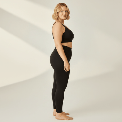 Legging Sculptant Grande Taille noir, vue de profil, studio ivoire gris clair, femme blonde 39 ans, pieds nus