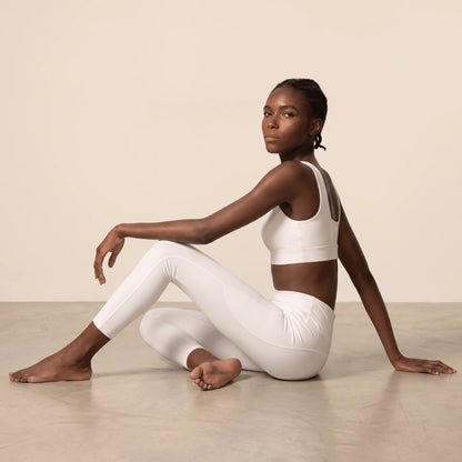 Legging yoga blanc : femme assise au sol en posture de détente, maille douce et extensible qui suit chaque mouvement