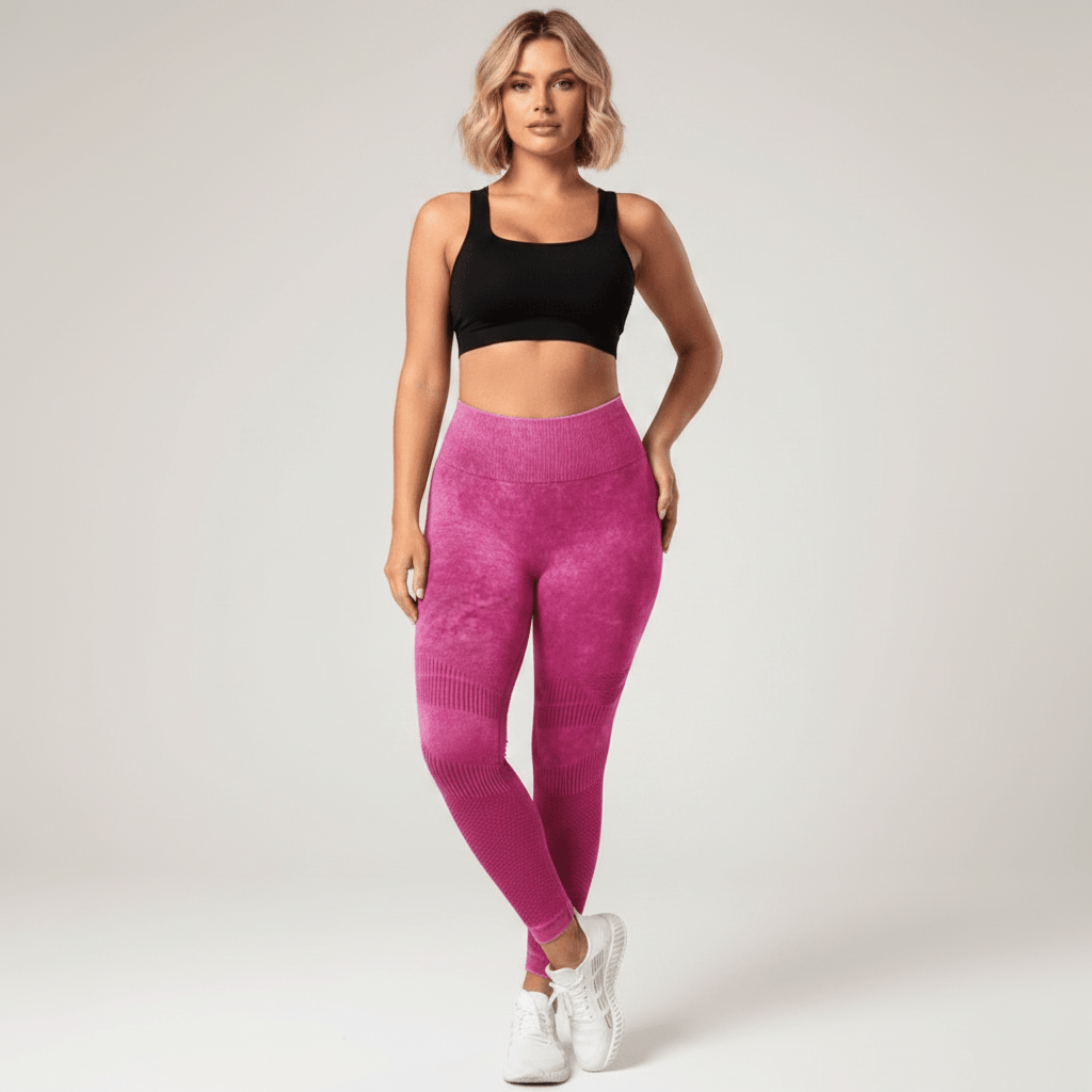 Legging Strong Push Up fuchsia/rose taille haute, vue de face pose élégante et confiante jambes légèrement croisées, maintien et compression visibles, brassière noire et baskets blanches, studio fond crème.