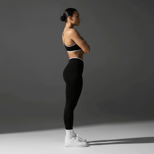 Porteuse de push up leggings sport noire, debout de profil, bras croisés, découvrez l’élégance dynamique pour la performance.