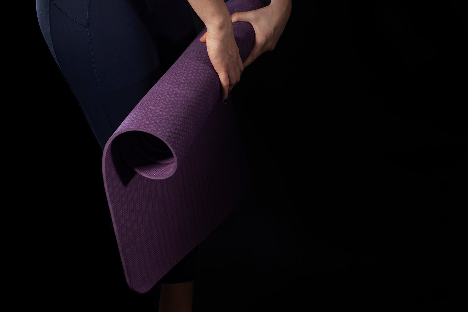 pliage d'un tapis de yoga mauve par une personne