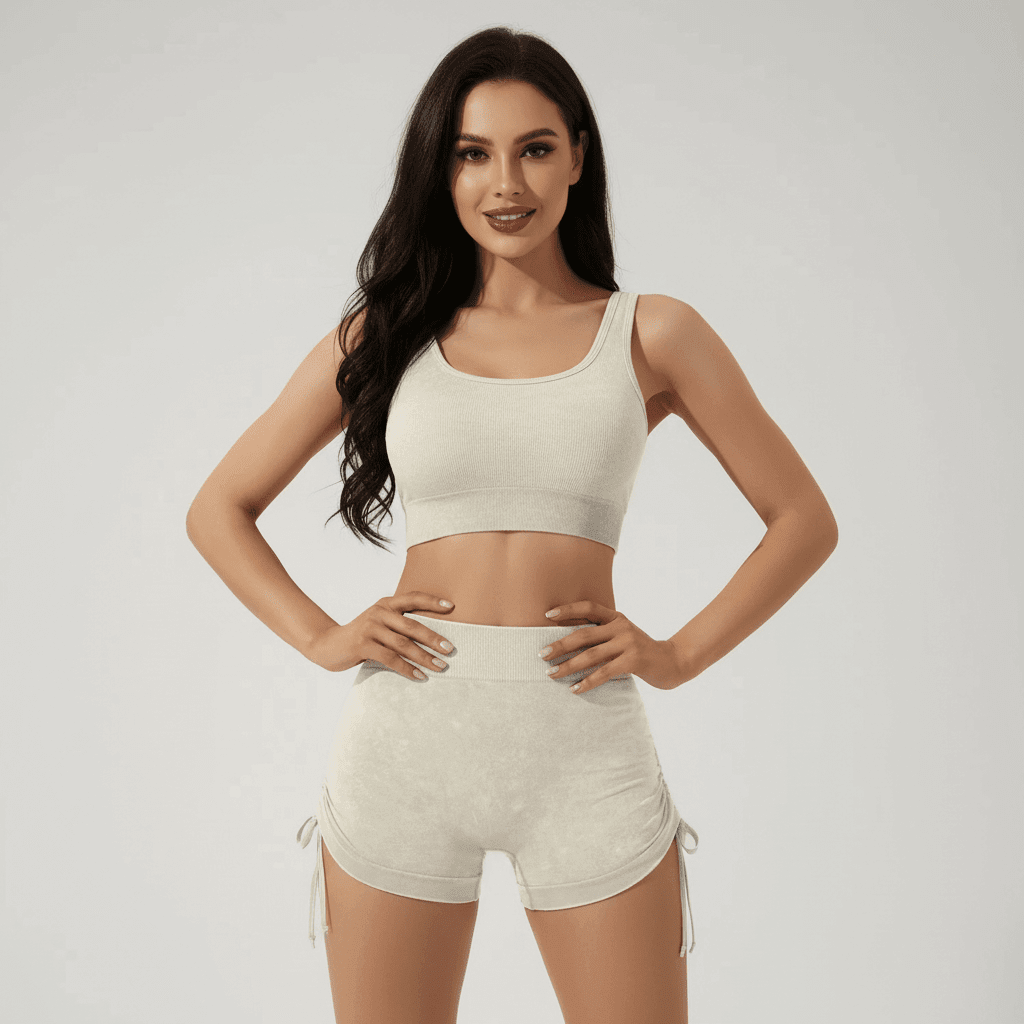 Haut de sport blanc et short assorti, femme debout souriante, hands on hips, scène crisp et respirante. Shorty fitness femme | Sculptant respirant.