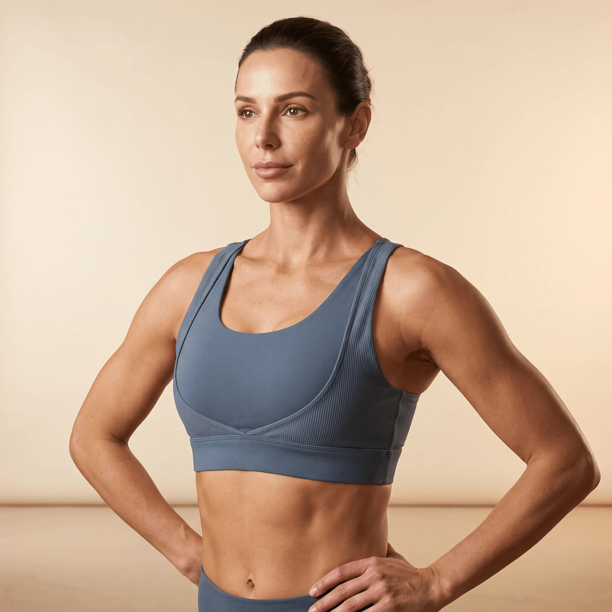 Soutien-gorge sportif bleu ardoise porté, mains sur les hanches, vue de trois quarts