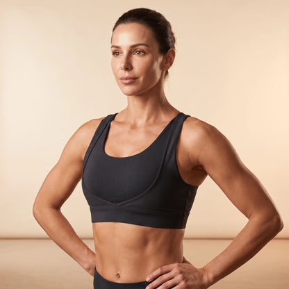 Soutien-gorge sportif noir porté, mains sur les hanches, vue de trois quarts