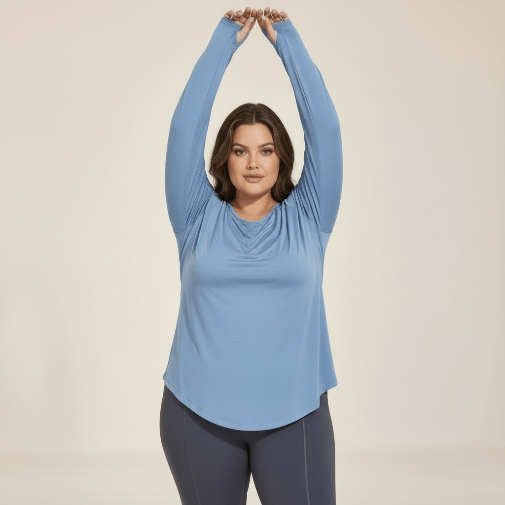 Femme portant un haut manches longues grande taille bleu gris, vue de face en léger mouvement, liberté d'épaule et manches raglan, studio fond ivoire.