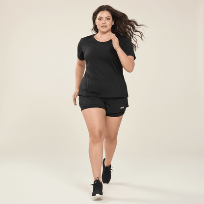 T-shirt running noir femme vu de face en marche, coupe couvrante sur les hanches