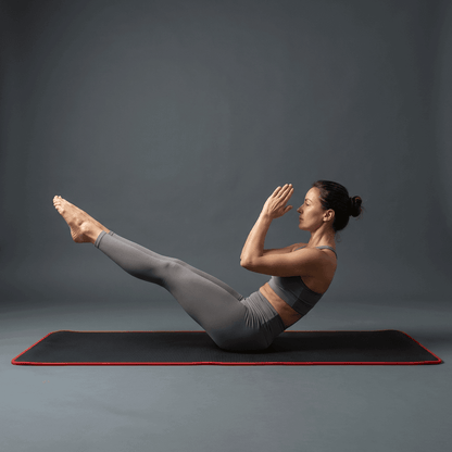 Femme en exercice pilates sur tapis de gym noir et rouge, photo lifestyle premium studio anthracite.