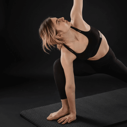 Femme en posture de yoga sur un tapis du sport MaxFit antidérapant, photo studio fond noir premium
