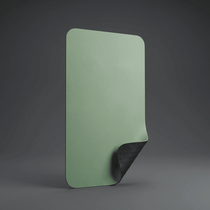 Tapis de yoga TPE vert sauge debout sur fond anthracite premium, avec un pli en bas révélant le verso noir antidérapant.