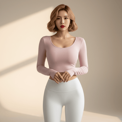 Top dos ouvert croisé femme rose pâle manches longues – vue de face mains jointes, décolleté scoop, legging blanc assorti, femme blonde carré wavy fond studio ivoire