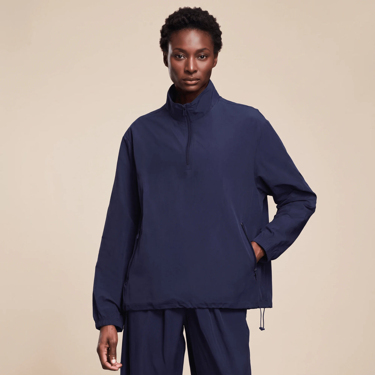 Veste running femme imperméable bleu marine, demi-zip remonté et ourlet resserré