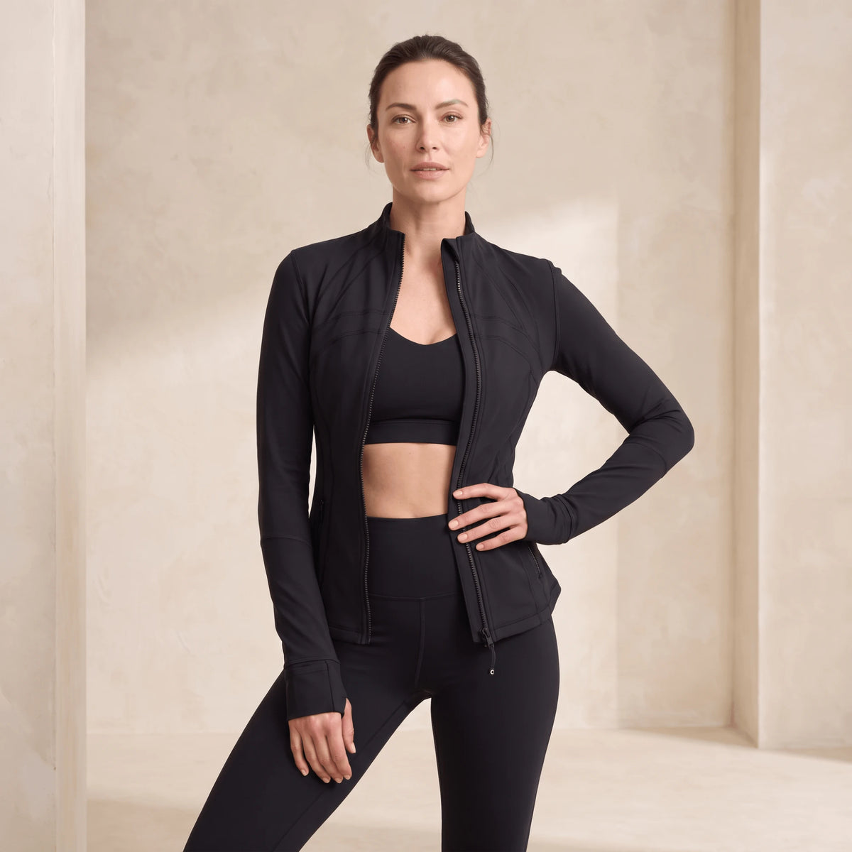 Veste sport femme doublée polaire noire ouverte sur une brassière, zip intégral