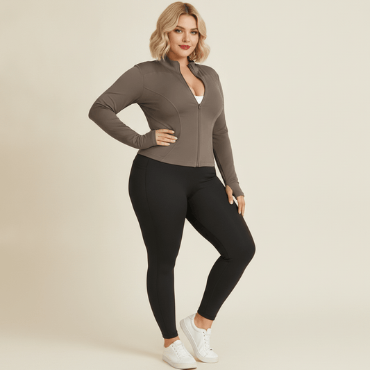 Veste sport grande taille femme taupe portée ouverte sur une brassière, allure fashion sport, fond studio crème
