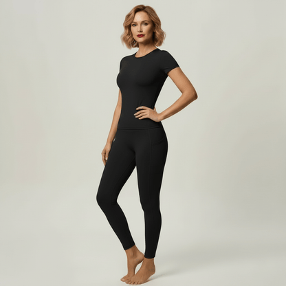 Vêtement crossfit femme — ensemble 2 pièces noir, t-shirt manches courtes et legging taille haute, pose 3/4 glamour studio